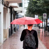 Una mujer se protege de la lluvia con un paraguas mientras camina por una calle de Córdoba