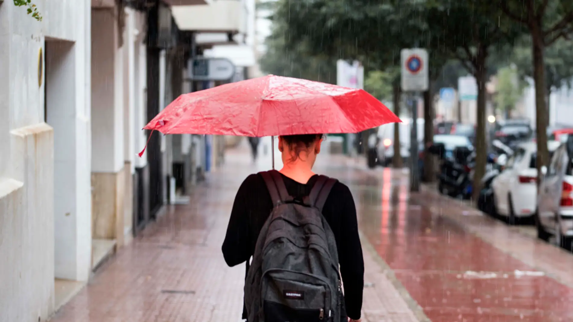  Una mujer se protege de la lluvia con un paraguas mientras camina por una calle de Córdoba