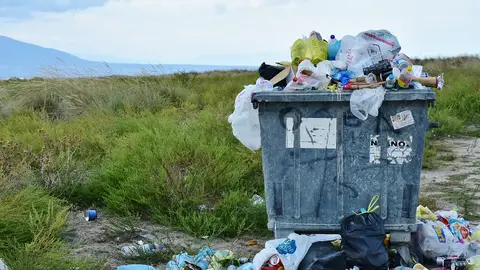 Un contenedor de basura lleno de plásticos en el campo Un contenedor de basura lleno de plásticos en el campo