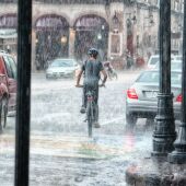 Imagen de archivo de un ciclista yendo por la calle en mitad de un diluvio