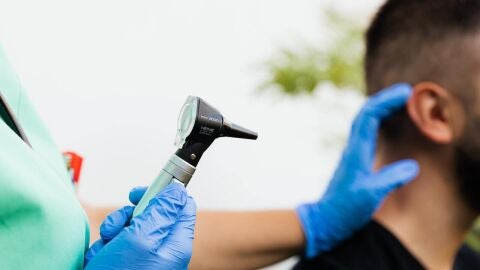 Un m&eacute;dico examina con un otoscopio a un paciente