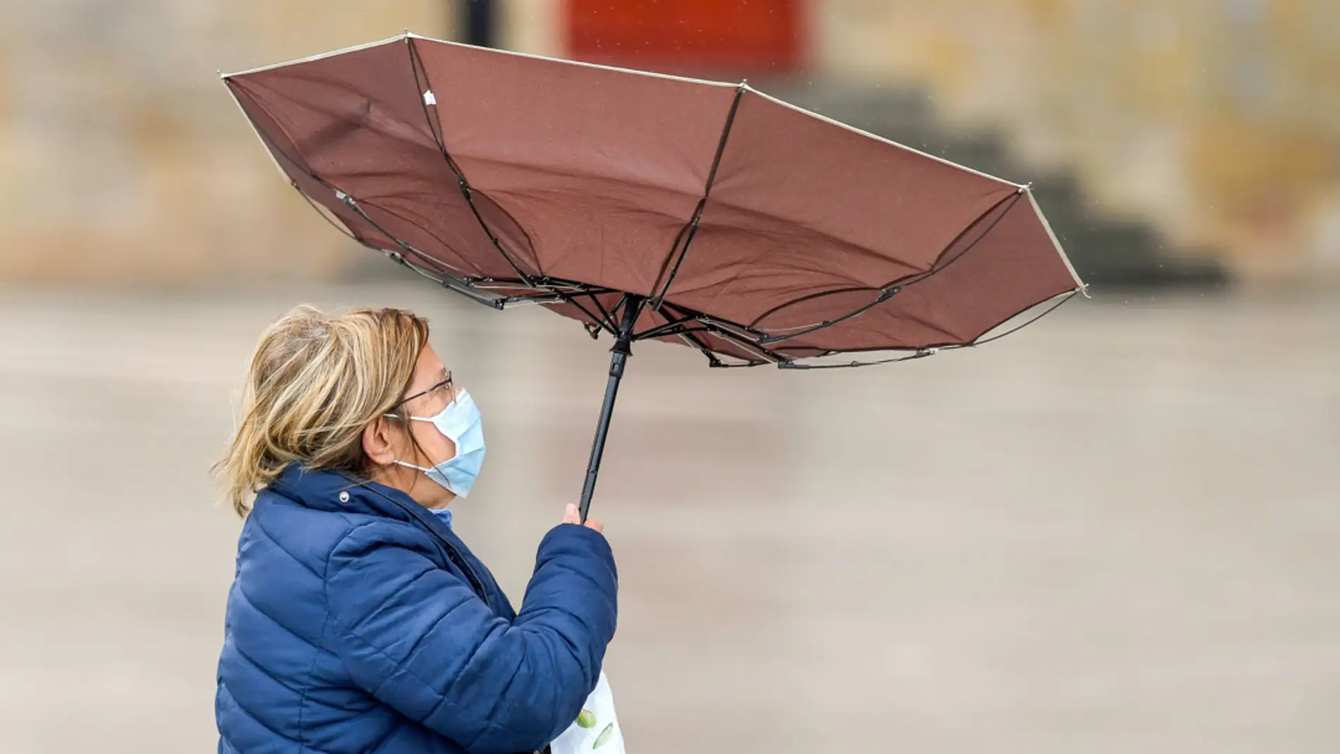 Una mujer camina en un día lluvioso y de mucho viento en Gijón