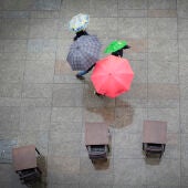 Varias personas se protegen de la lluvia con un paraguas en Pamplona.