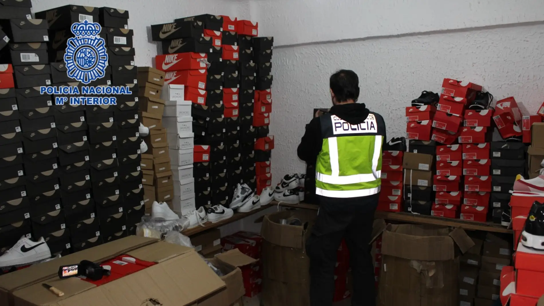 Agente de la Policía Nacional junto a parte de los productos falsificados incautados. 