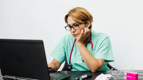 Una enfermera trabajando con el ordenador Alemania busca enfermeros en España: requisitos para cobrar hasta 2.400 euros