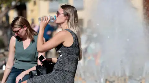 En la imagen, dos jóvenes se refrescan en una fuente del centro de la ciudad de Valencia. En la imagen, dos jóvenes se refrescan en una fuente del centro de la ciudad de Valencia.