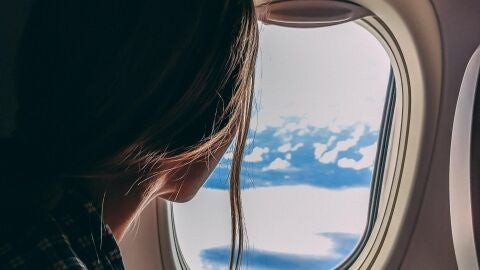 Imagen de una mujer mirando por la ventana de un avi&oacute;n