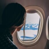 Imagen de una mujer mirando por la ventana de un avión