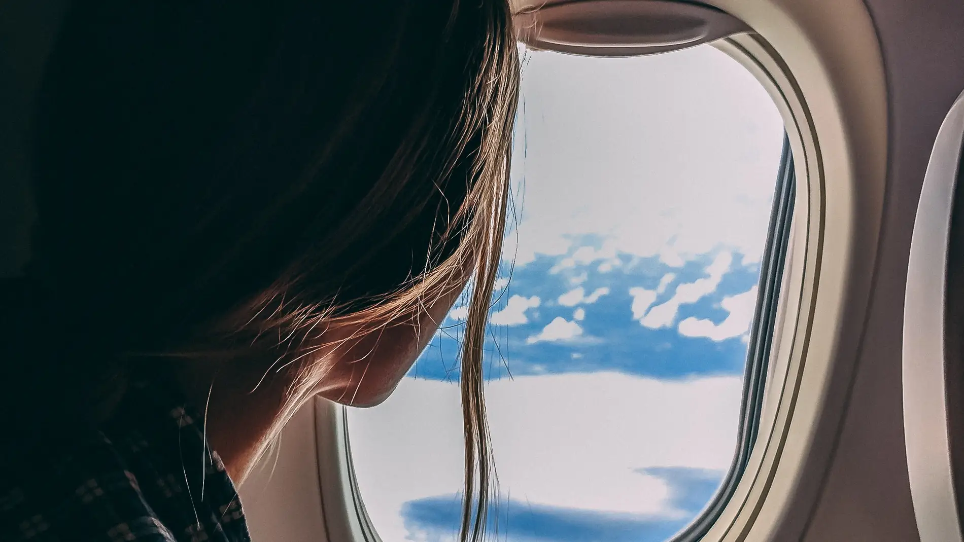 Imagen de una mujer mirando por la ventana de un avión