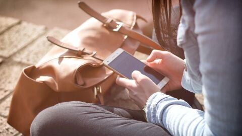 Imagen de una joven manipulando un tel&eacute;fono m&oacute;vil