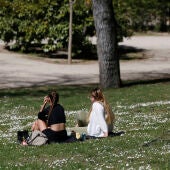 Varias personas disfrutan del sol en un parque, en una jornada marcada por las temperaturas primaverales en la capital de España. 