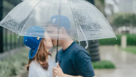 Pareja besándose bajo un paraguas Pareja besándose bajo un paraguas
