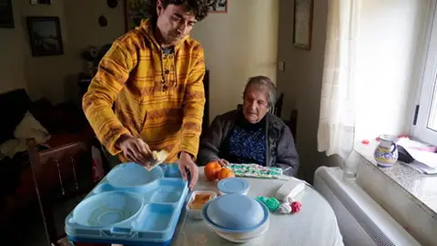 Un repartidor entrega un menú del servicio “Menjar a Domicili” menjar