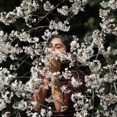 Imagen de una joven oliendo un cerezo en flor
