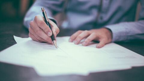 Imagen de archivo de una persona que firma un papel.