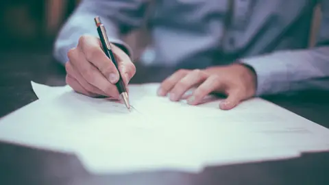 Imagen de archivo de una persona que firma un papel. Imagen de archivo de una persona que firma un papel.