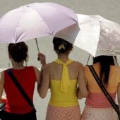 Fotografía de archivo de tres jóvenes que se protegen del sol con un paraguas