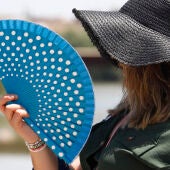 Una mujer se protege de las altas temperaturas con un sombrero y un abanico, en una fotografía de archivo