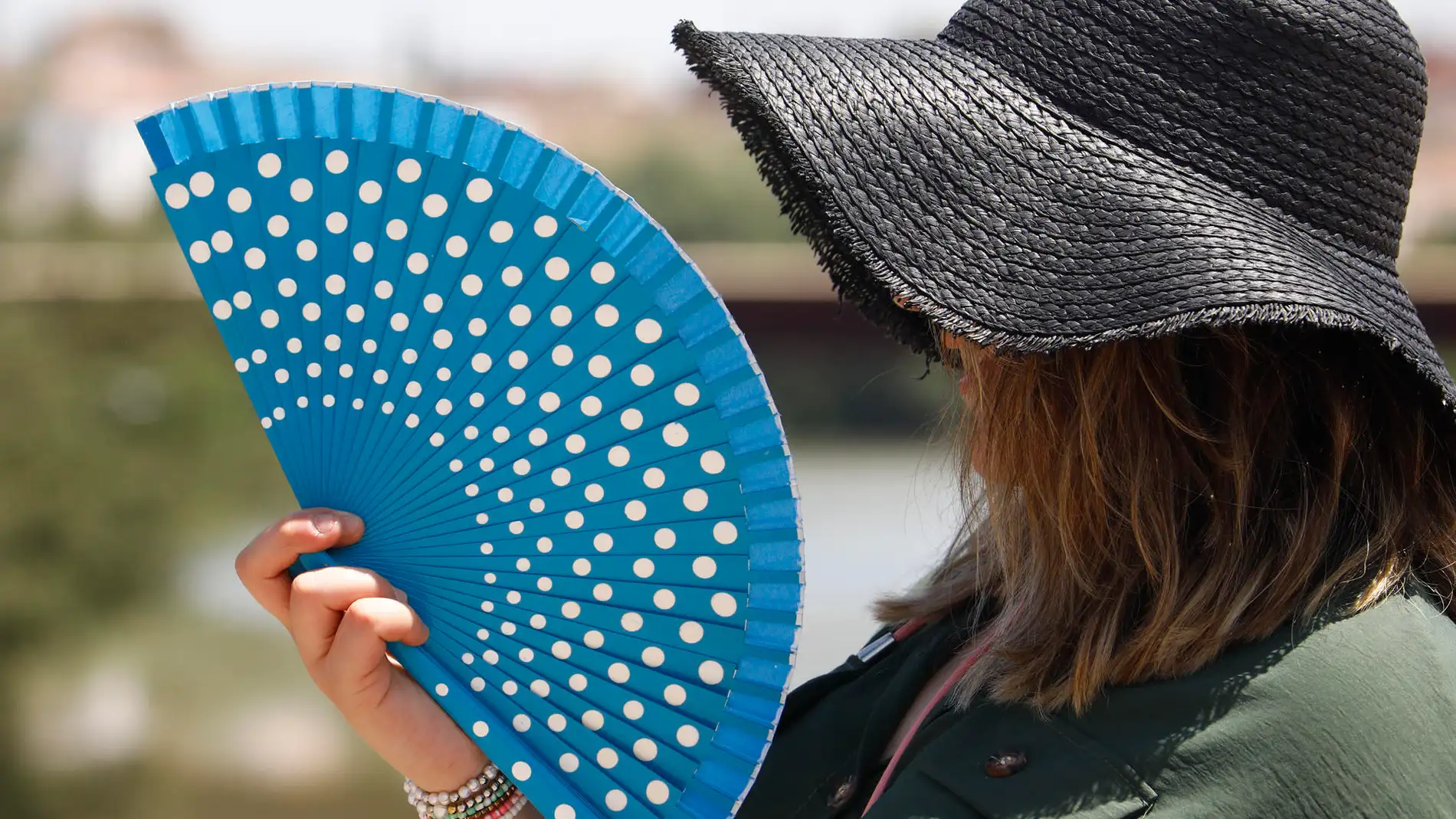 Una mujer se protege de las altas temperaturas con un sombrero y un abanico, en una fotografía de archivo