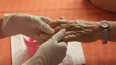 Una mano de una persona anciana sostenida por una cuidadora Una mano de una persona anciana sostenida por una cuidadora