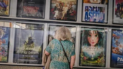 Una señora mayor frente a la cartelera de unos cines/ Agostime / Europa Press