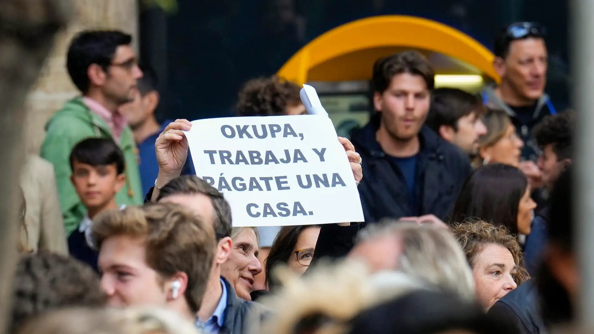 Una mujer muestra una pancarta contra las ocupaciones durante una concentración en Barcelona.