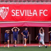 Los jugadores del Sevilla estiran sobre el césped de la Ciudad Deportiva.