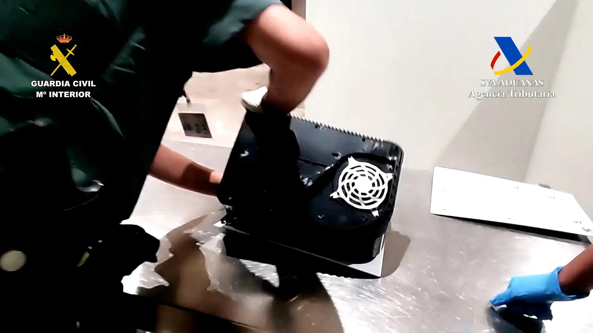 Agente de la Guardia Civil desmonta la videoconsola en cuyo interior se ha encontrado la cocaína. 