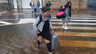 Varias personas cruzan una calle inundada durante el episodio de lluvias torrenciales en Castelló
