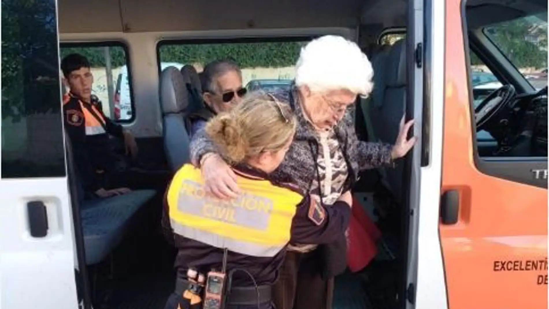Voluntaria de protección civil ayuda a una anciana.