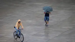 En la imagen de archivo, dos personas se protegen de la fina lluvia en Pamplona. 