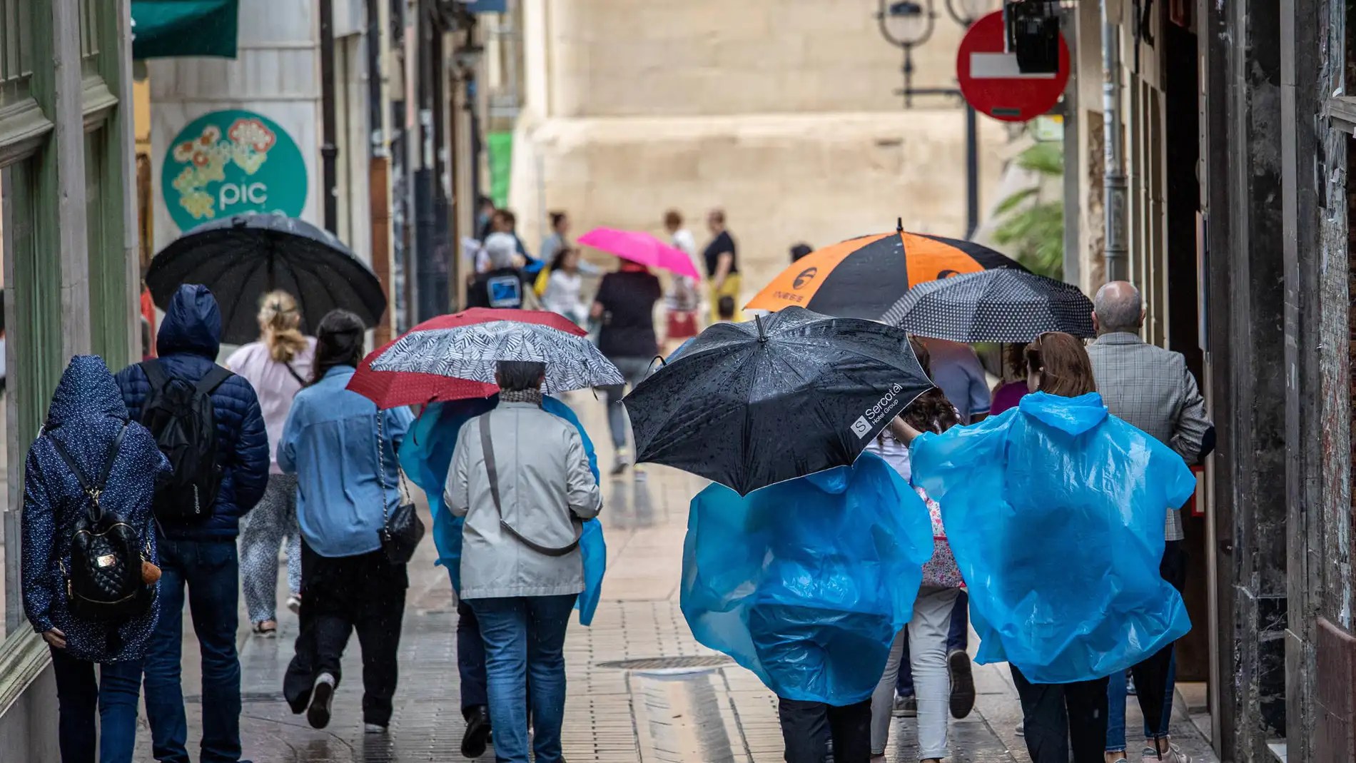 Turistas y transeúntes caminan bajo la lluvia en Logroño.