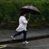 En la imagen de archivo, una mujer se protege de la intensa lluvia en Oviedo