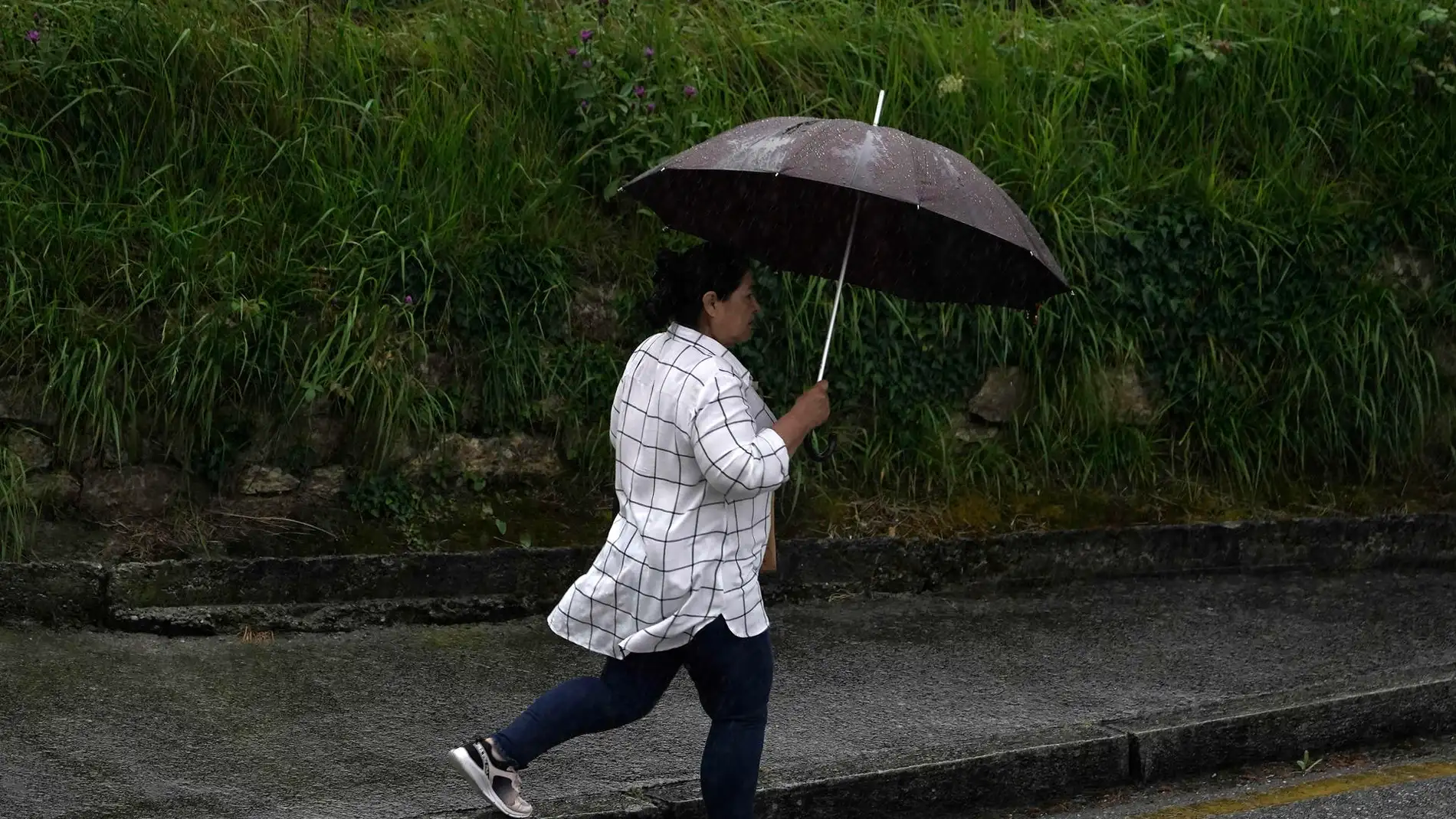 En la imagen de archivo, una mujer se protege de la intensa lluvia en Oviedo