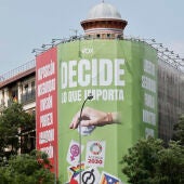 Vista de la lona del odio instalada por VOX en la que se muestra la bandera LGTBI+ en una papelera en la calle Alcalá de Madrid 