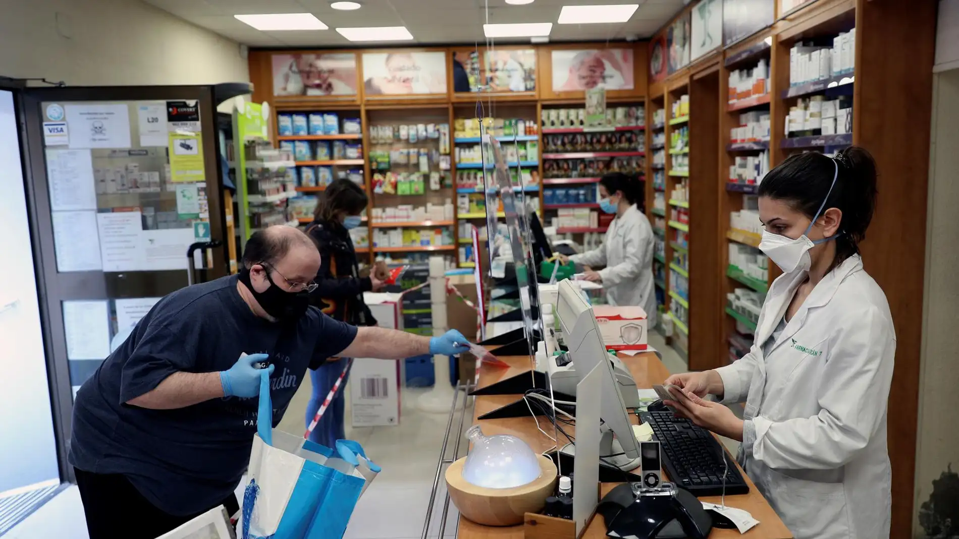 Dos personas son atendidas en una farmacia de Madrid. 