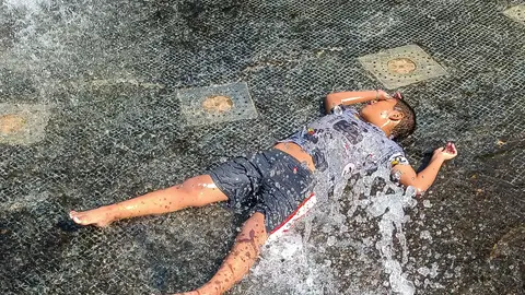 Imagen de archivo de un niño bañándose en una fuente durante una ola de calor Temperaturas récord el primer fin de semana del verano: más de 40 grados durante varios días