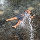 Imagen de archivo de un niño bañándose en una fuente durante una ola de calor