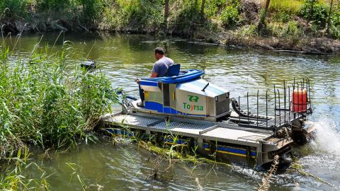 Barco anfibio cortando plantas acu&aacute;ticas en el r&iacute;o Henares