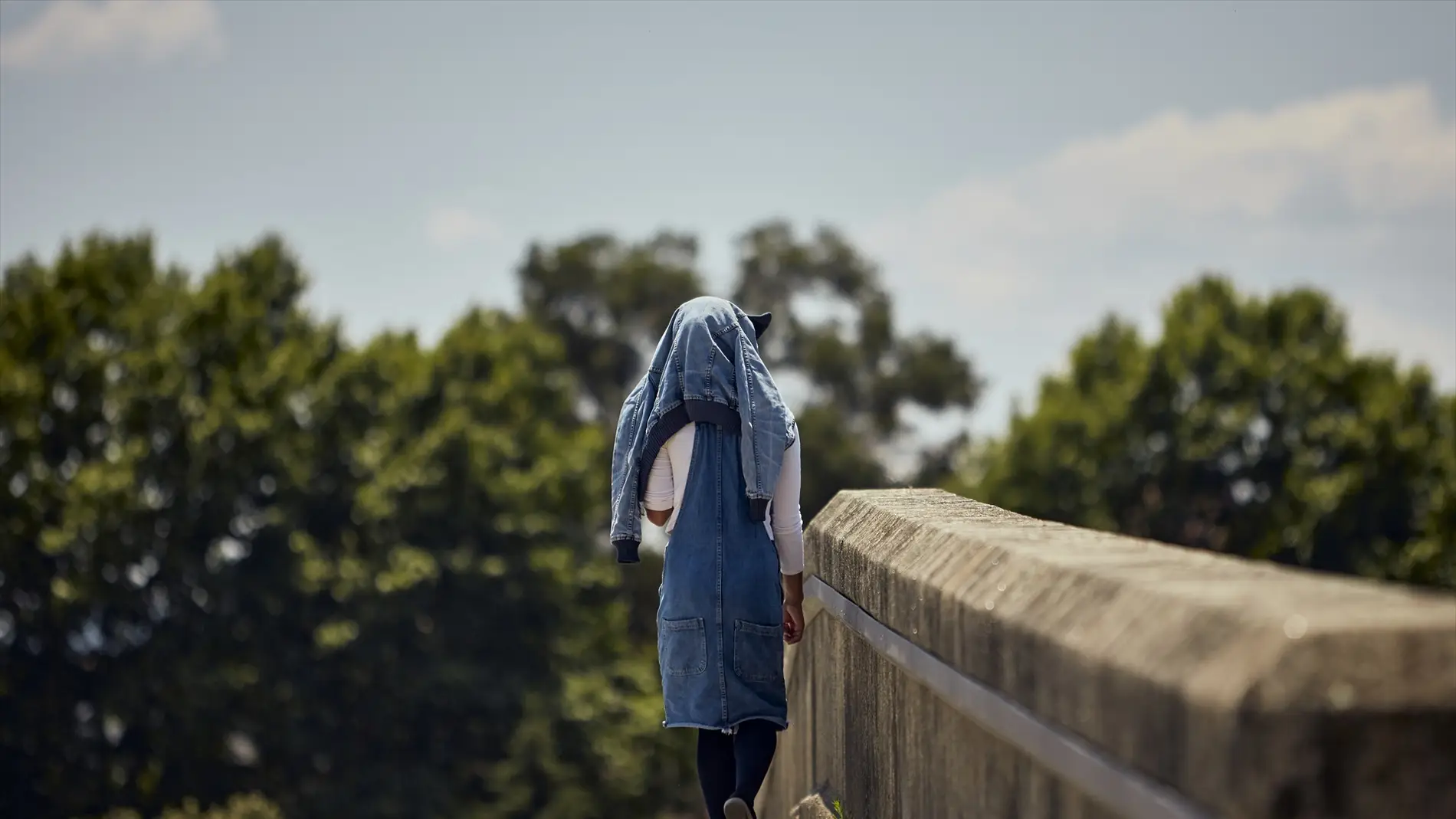 Una joven se tapa del calor con una chaqueta en la cabeza.