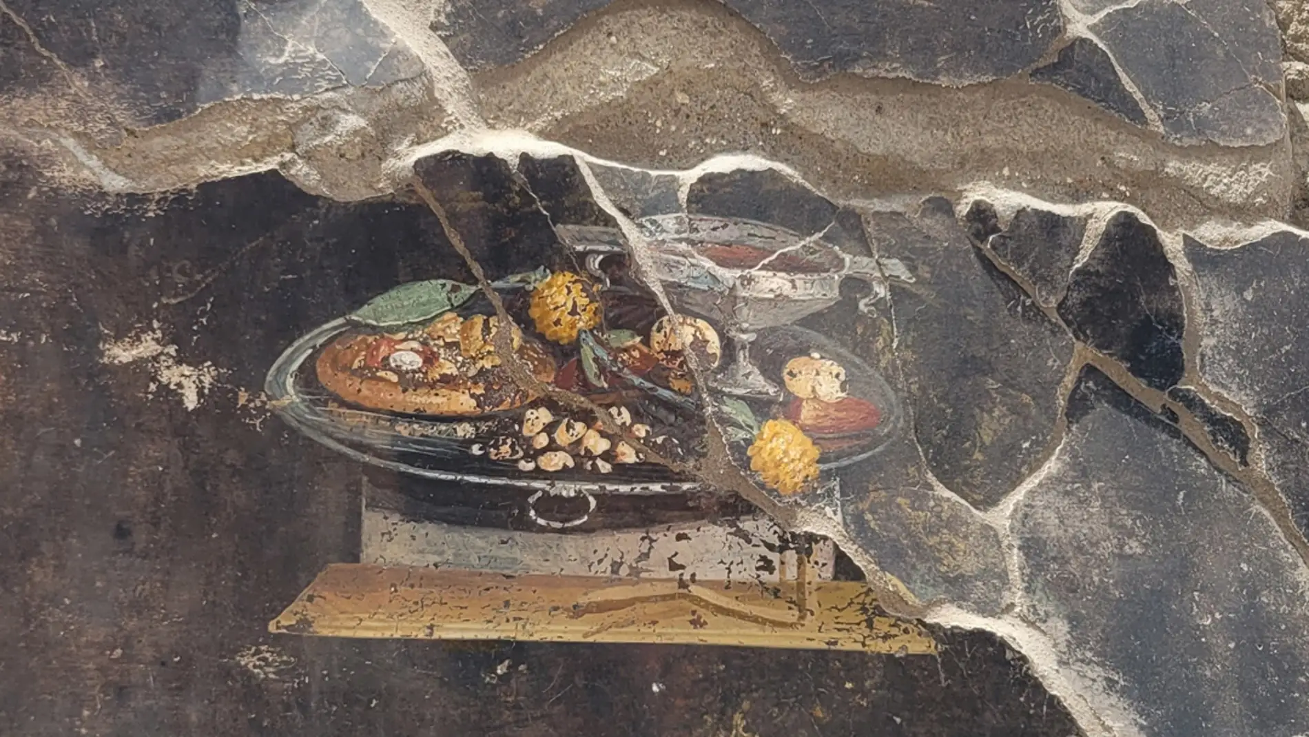 Imagen del fresco encontrado en Pompeya donde aparece lo que podría ser un plato antepasado de la actual pizza