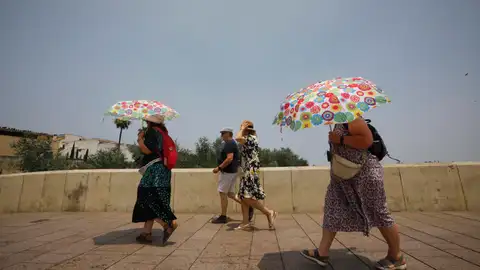 Varios turistas se cubren con sombrillas mientras cruzan el Puente Romano de Córdoba. Varios turistas se cubren con sombrillas mientras cruzan el Puente Romano de Córdoba.