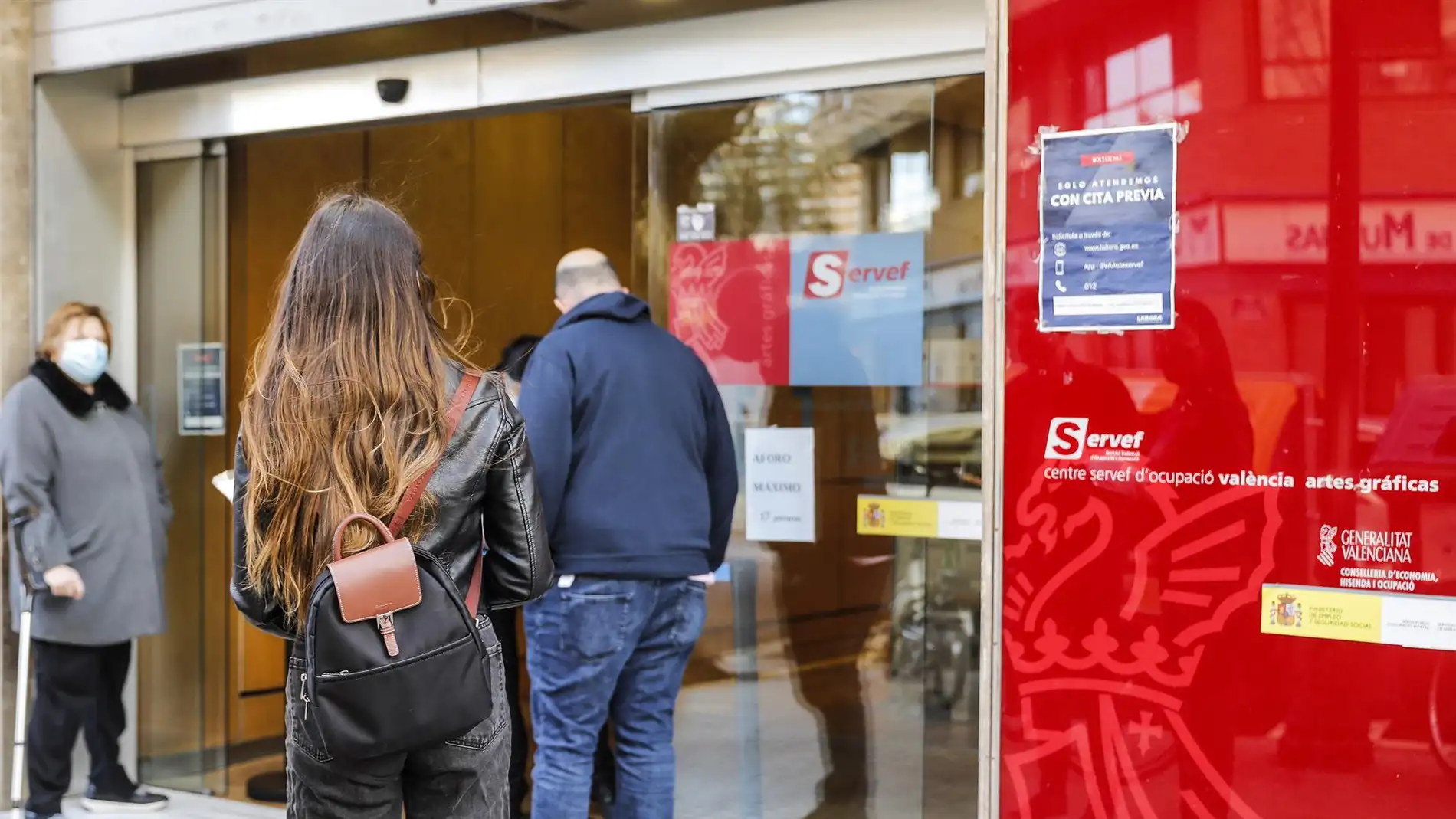 Archivo - Varias personas con cita previa esperan para entrar en una oficina del SERVEF, en València.