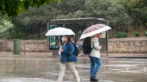 Dos personas con paraguas cruzan una calle de Jaén, en una fotografía de archivo. Dos personas con paraguas cruzan una calle de Jaén, en una fotografía de archivo.