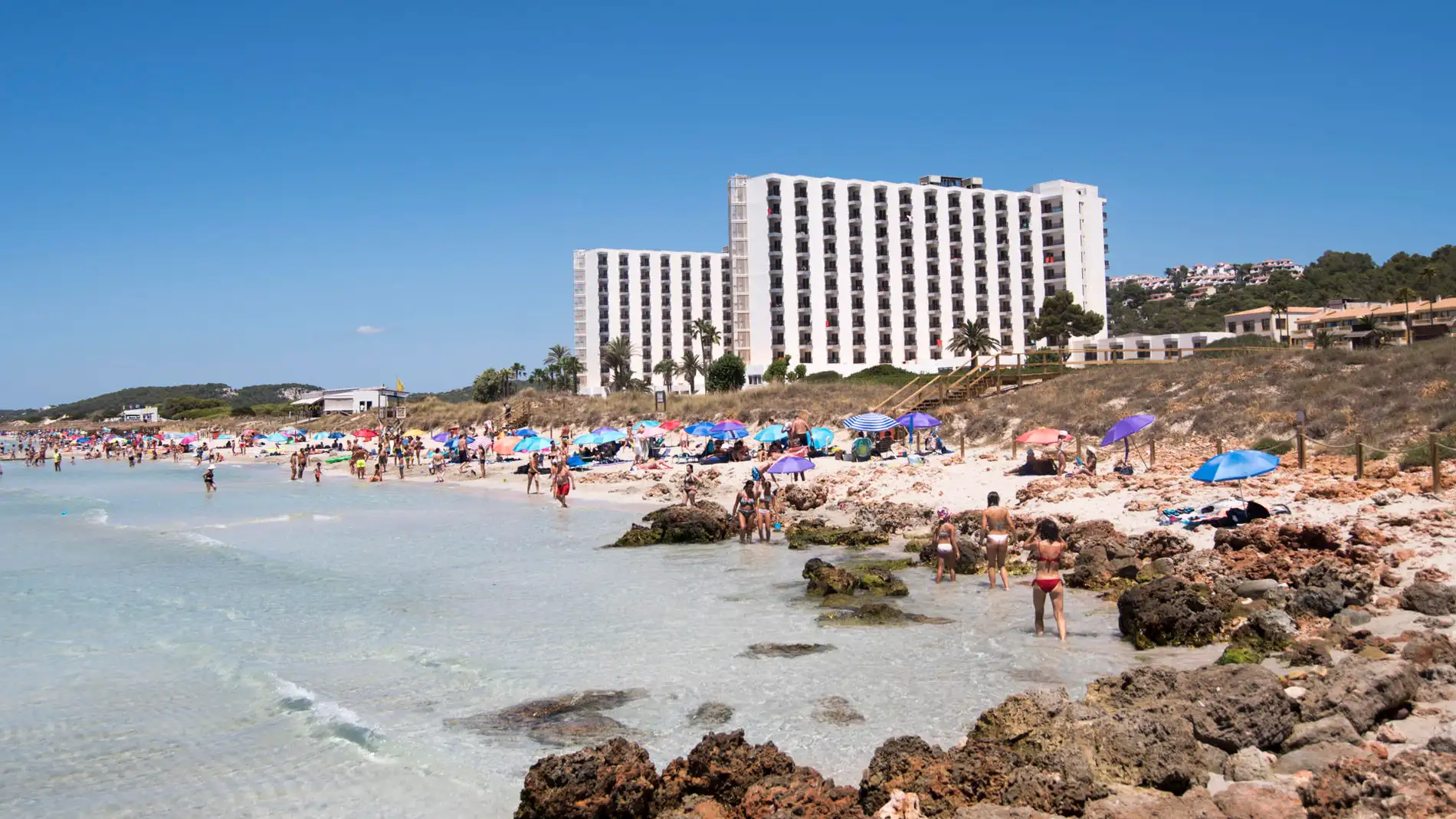 Varias personas difrutan de un día soleado en una playa de Menorca