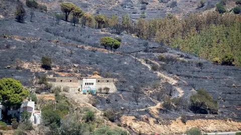 Vista de las zonas afectadas por el incendio que comenzó ayer en Portbou (Girona), y que en estos momentos sigue activo. Los bomberos remojan el incendio de Portbou tras producirse pequeñas reanudaciones de madrugada