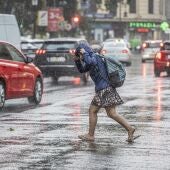 Una mujer anda por la calle bajo la lluvia.