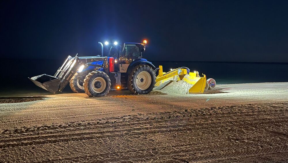 Un tractor pasa el rastrillo en una playa de Elche