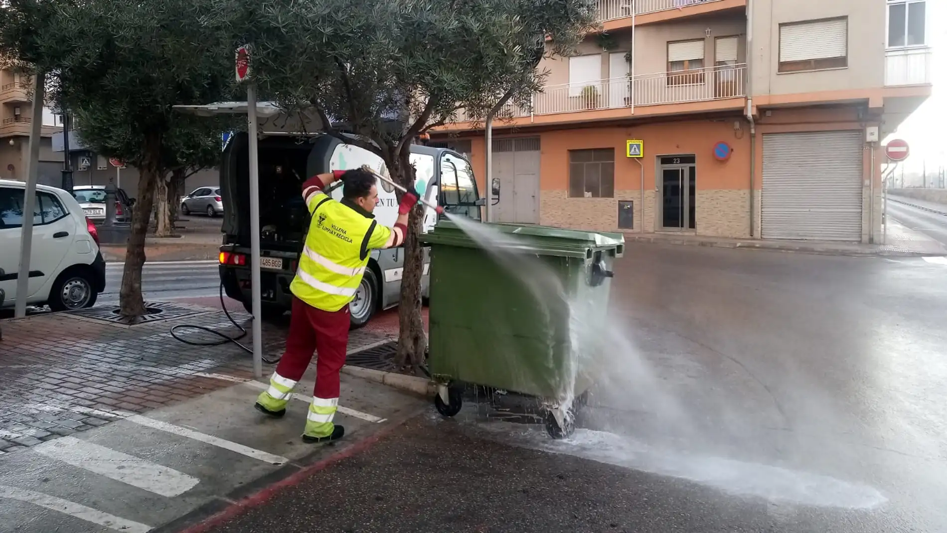 Un trabajador limpiando uno de los contenedores del casco urbano de Villena. 