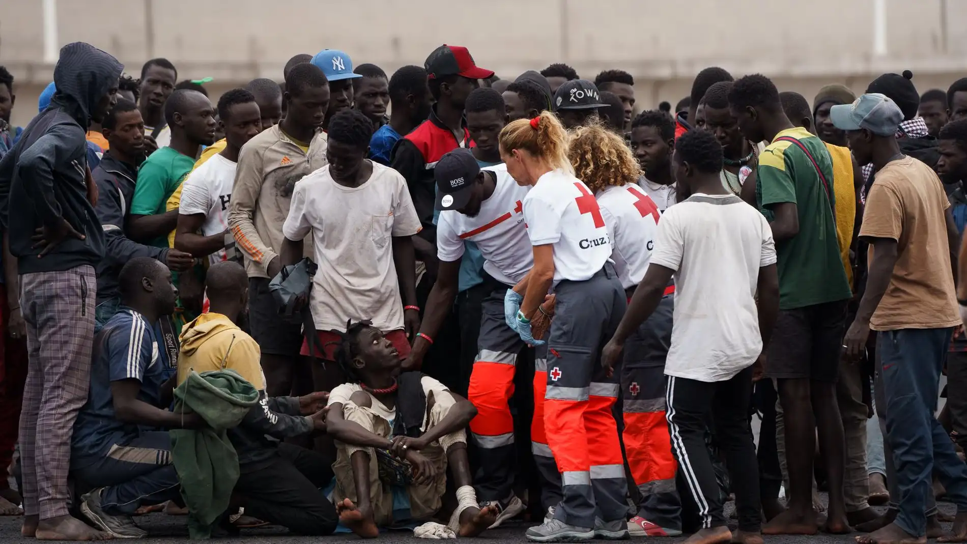Un grupo de inmigrantes de los llegados a Canarias, ya en el puerto, son atendidos por personal de Cruz Roja